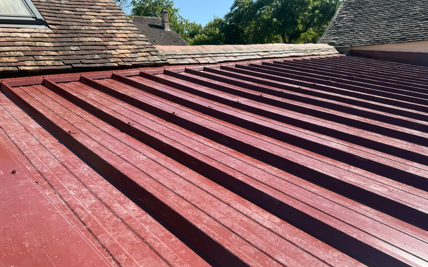 Pose de bac acier et faîtage en tôle sur mesure sous une toiture en tuiles plates